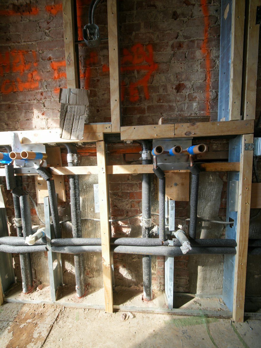 Instalación de fontanería con tuberías de cobre y estructura en pared de ladrillo.